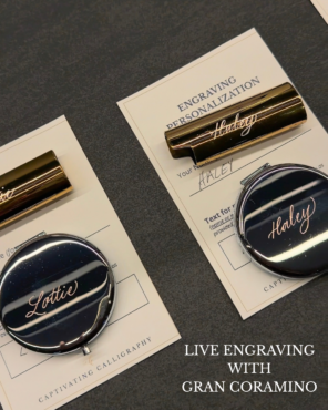 Gold lighter cases and silver compact mirrors hand engraved with the names "Haley" and "Lottie" in calligraphy script, shown on engraving personalization cards at a Gran Coramino brand activation by Captivating Calligraphy.
