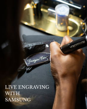 Calligrapher hand engraving the name "Georgia" in script lettering on a silver metal card case during a live engraving activation at a Samsung corporate event by Captivating Calligraphy.